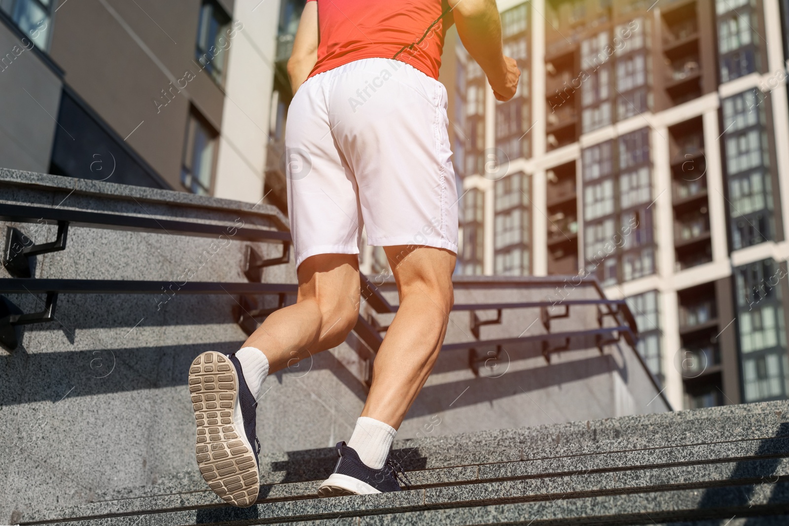 Man in sportswear running up on stairs outdoors, low angle view. Space for text Photo of Man in sportswear running up on stairs outdoors, low angle view. Space for text