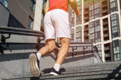 Photo of Man in sportswear running up on stairs outdoors, low angle view. Space for text