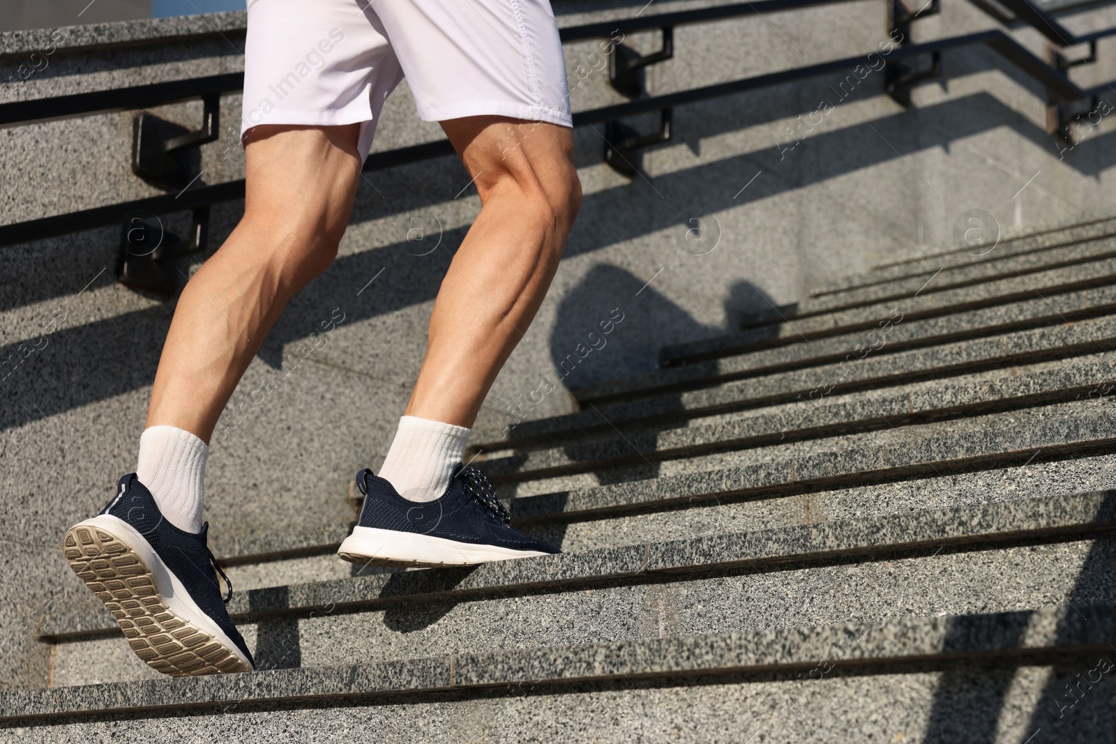 Photo of Man in sportswear running up on stairs outdoors, low angle view. Space for text