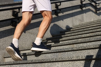 Photo of Man in sportswear running up on stairs outdoors, low angle view. Space for text