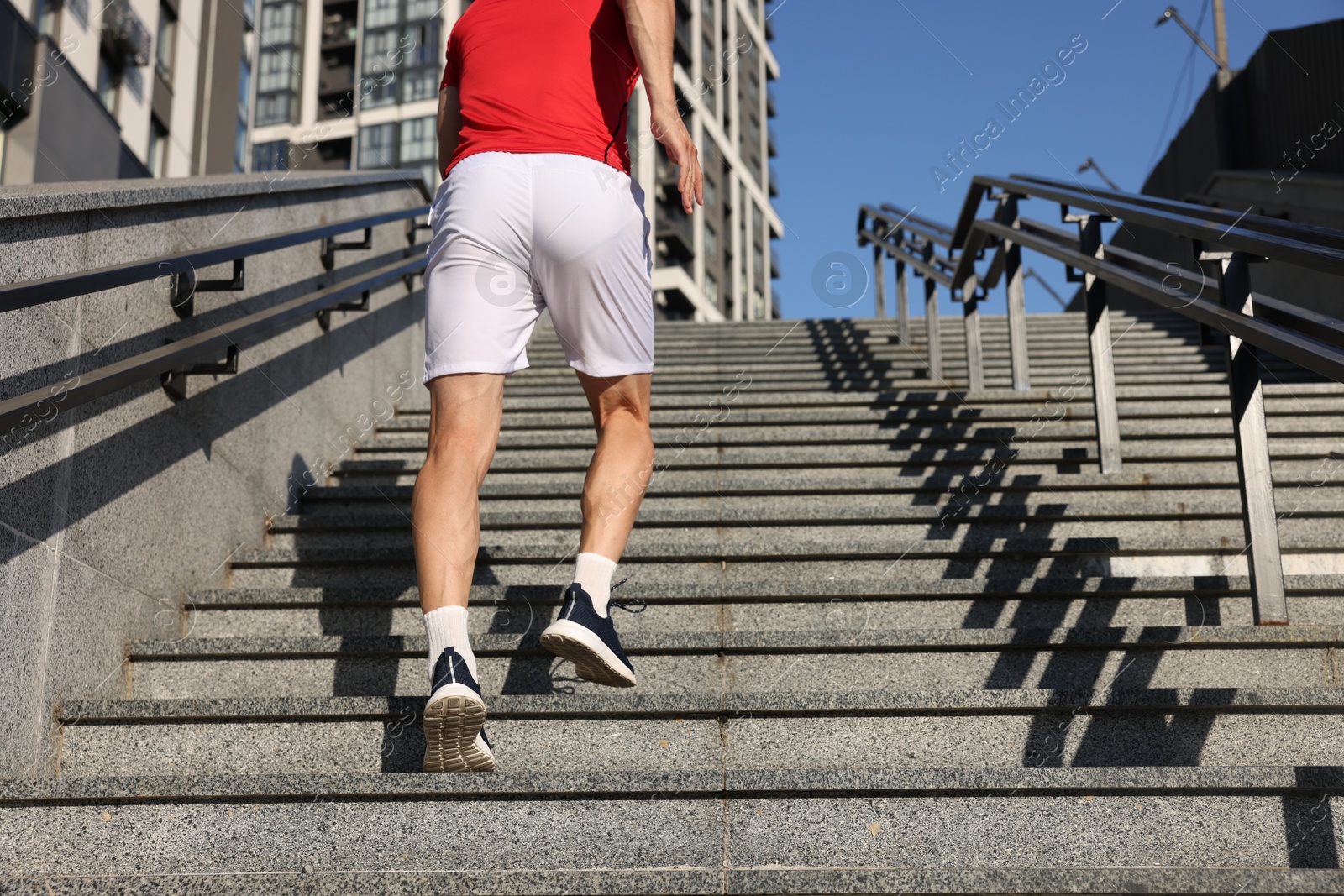 Photo of Man in sportswear running up on stairs outdoors, low angle view