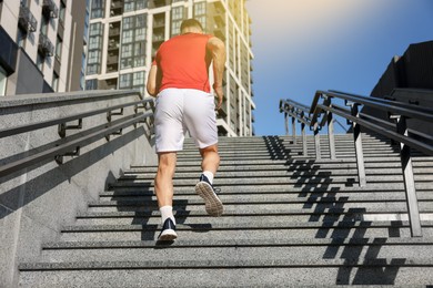 Photo of Man in sportswear running up on stairs outdoors, low angle view
