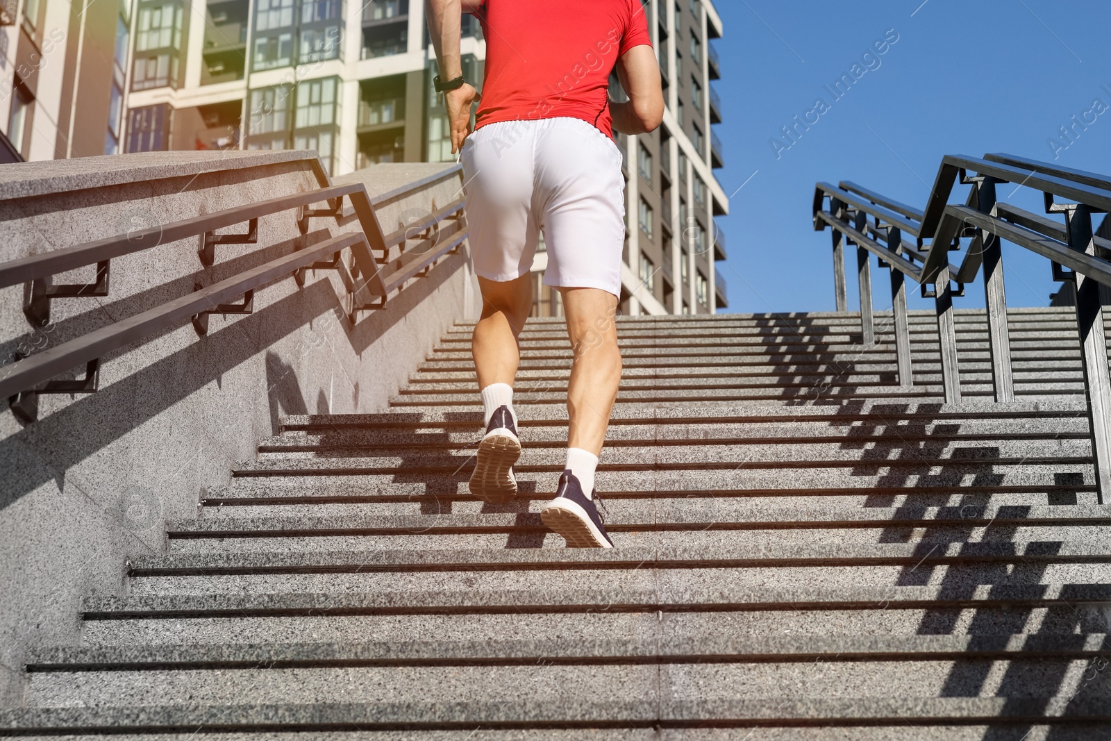 Man in sportswear running up on stairs outdoors, low angle view Photo of Man in sportswear running up on stairs outdoors, low angle view