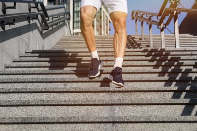 Photo of Man in sportswear running down on stairs outdoors, closeup