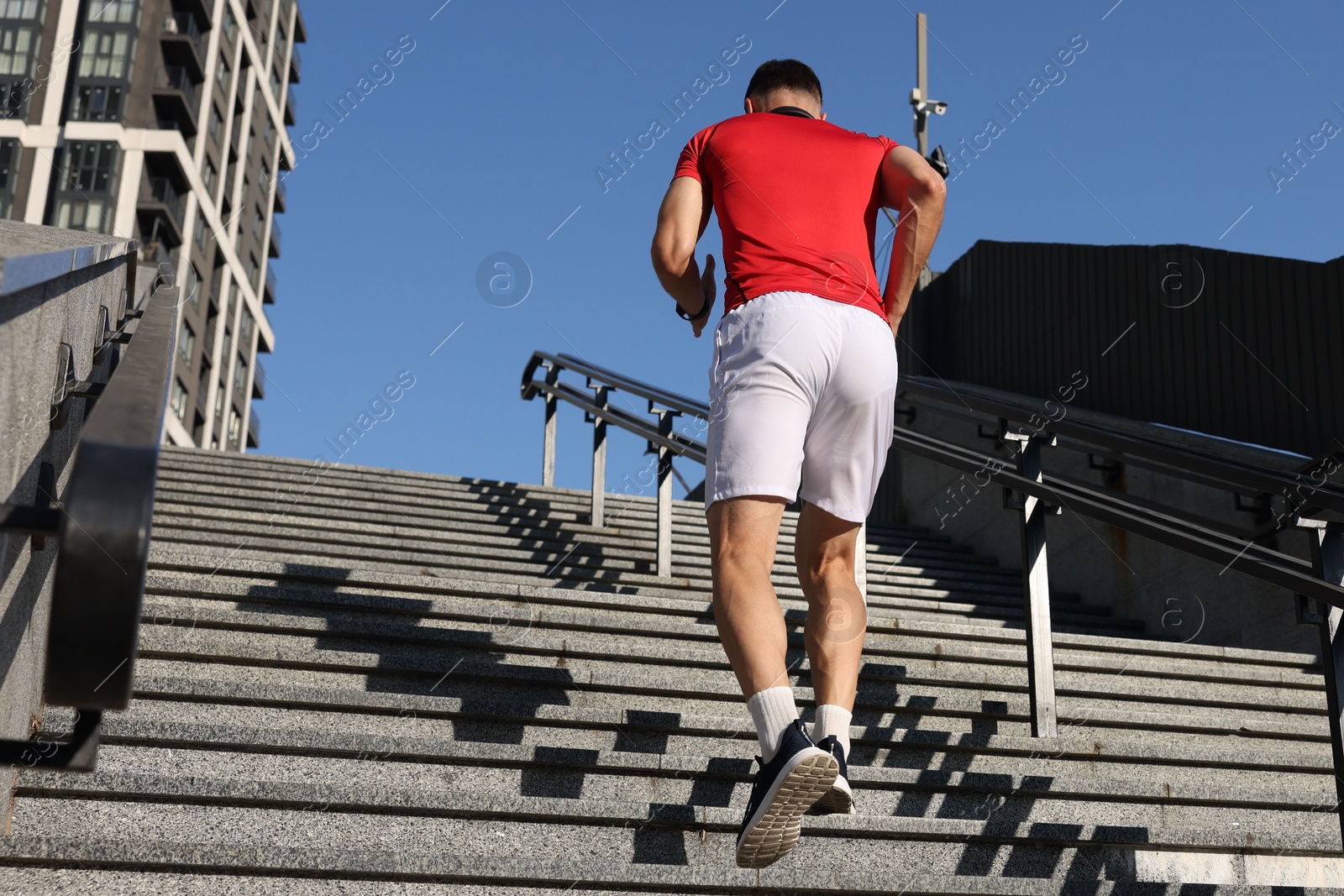 Man in sportswear running up on stairs outdoors, low angle view. Space for text Photo of Man in sportswear running up on stairs outdoors, low angle view. Space for text