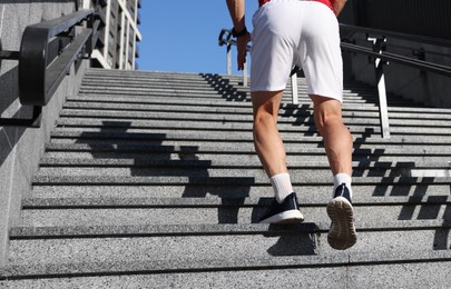 Photo of Man in sneakers running up on stairs outdoors, closeup. Space for text
