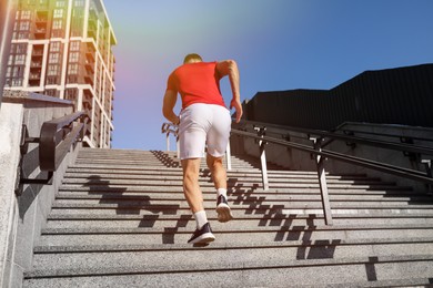 Photo of Man in sportswear running up on stairs outdoors, low angle view
