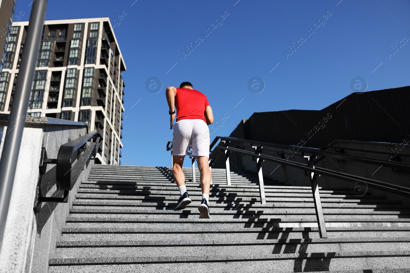 Photo of Man in sportswear running up on stairs outdoors, low angle view
