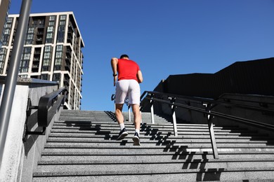 Photo of Man in sportswear running up on stairs outdoors, low angle view