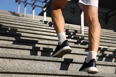 Photo of Man in sportswear running up on stairs outdoors, low angle view. Space for text