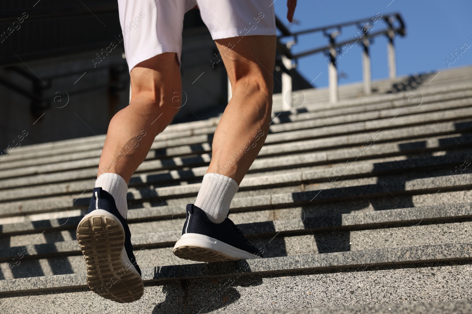 Photo of Man in sportswear running up on stairs outdoors, low angle view. Space for text