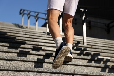 Photo of Man in sportswear running up on stairs outdoors, low angle view. Space for text
