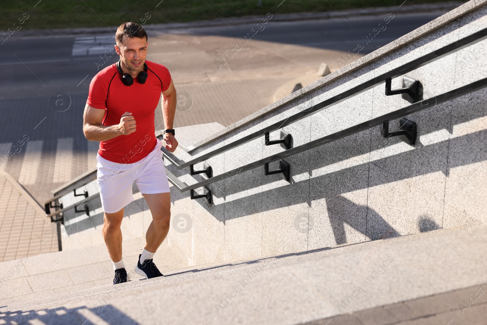 Photo of Man in sportswear running up on stairs outdoors