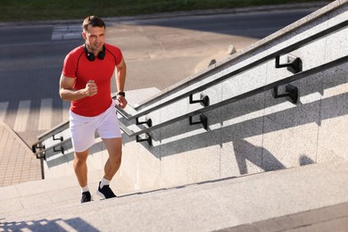 Photo of Man in sportswear running up on stairs outdoors