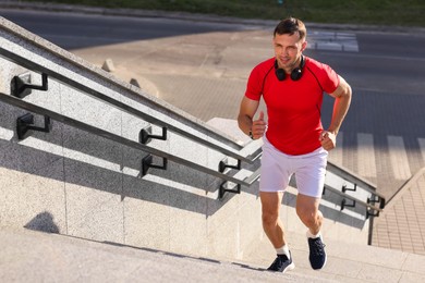 Photo of Man in sportswear running up on stairs outdoors