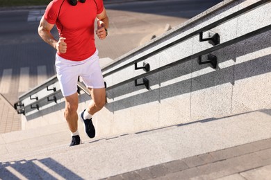 Photo of Man in sportswear running up on stairs outdoors, closeup