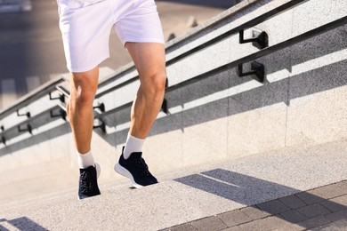 Photo of Man in sportswear running up on stairs outdoors, closeup. Space for text