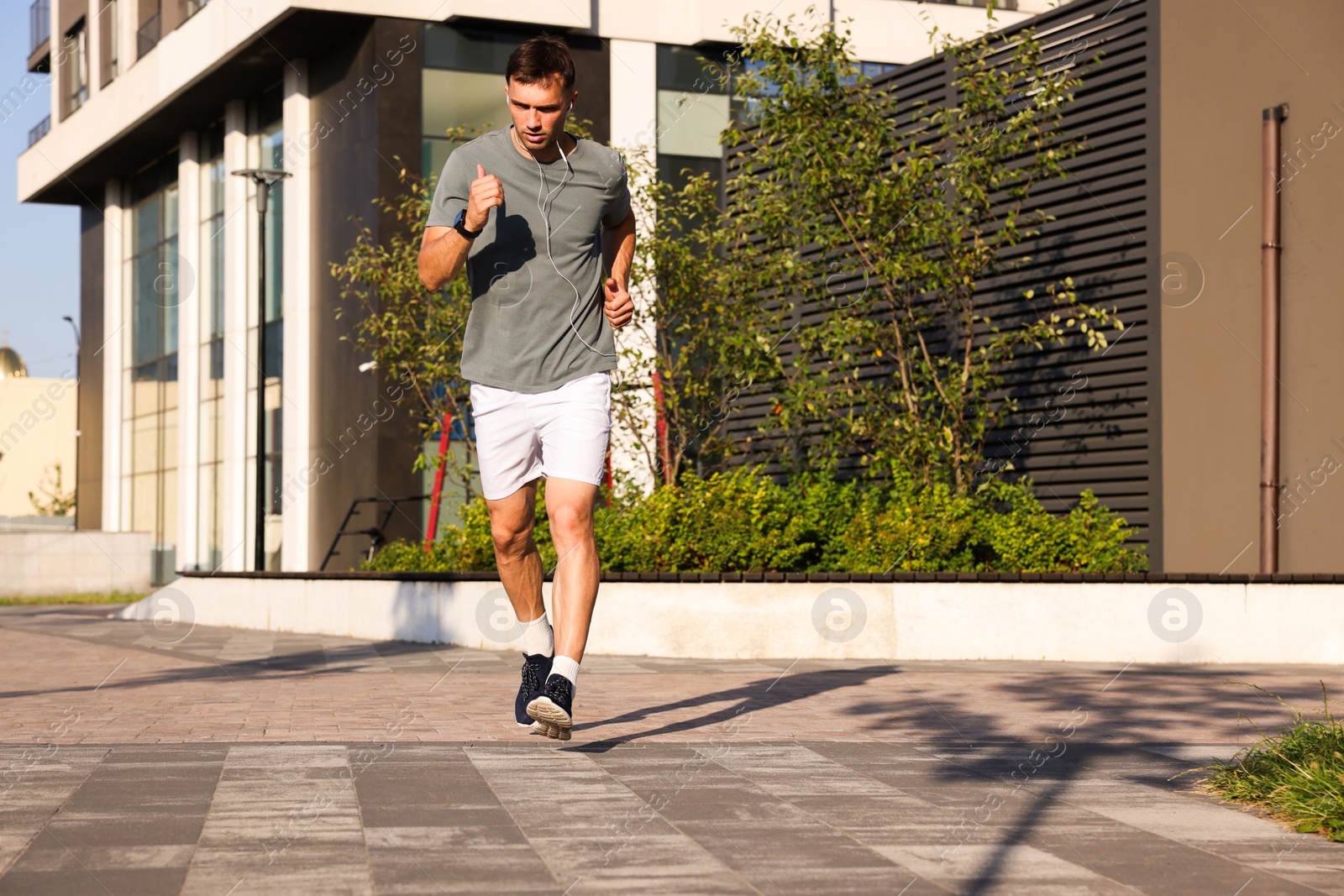 Man in earphones running outdoors on sunny day, space for text Photo of Man in earphones running outdoors on sunny day, space for text
