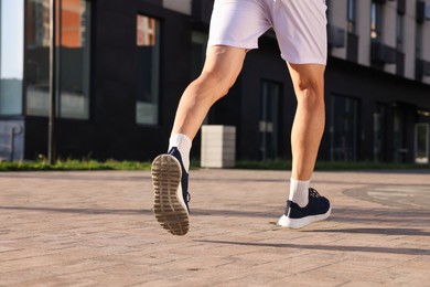 Photo of Man in stylish sneakers running outdoors, closeup. Space for text