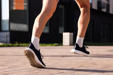 Photo of Man in stylish sneakers running outdoors, closeup