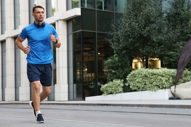 Photo of Man in sportswear running outdoors, space for text