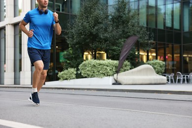 Photo of Man in sportswear running outdoors, closeup. Space for text