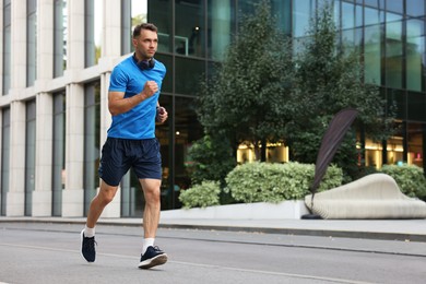 Photo of Man in sportswear running outdoors, space for text