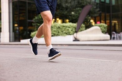 Photo of Man in stylish sneakers running outdoors, closeup. Space for text