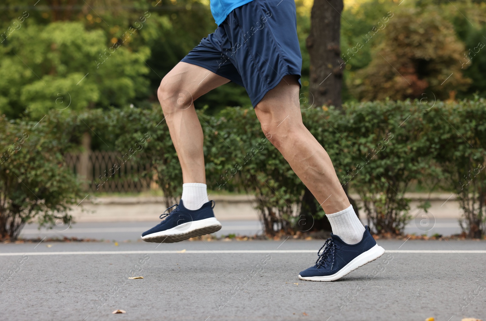 Photo of Man in stylish sneakers running outdoors, closeup