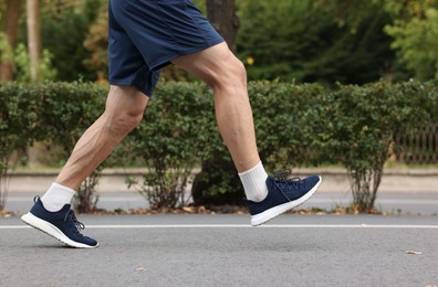 Photo of Man in stylish sneakers running outdoors, closeup