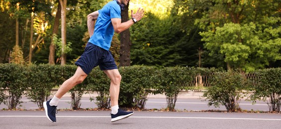 Photo of Man in sportswear running outdoors, closeup. Space for text