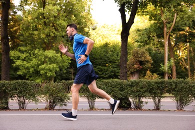 Photo of Man in sportswear running outdoors, space for text