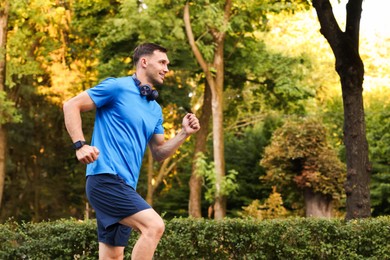 Photo of Man in sportswear running outdoors, space for text