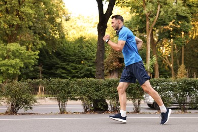 Photo of Man in sportswear running outdoors, space for text