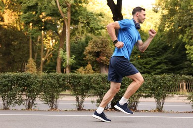 Photo of Man in sportswear running outdoors, space for text