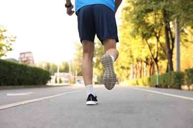 Photo of Man in sportswear running outdoors, back view