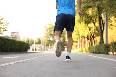 Photo of Man in sportswear running outdoors, back view. Space for text