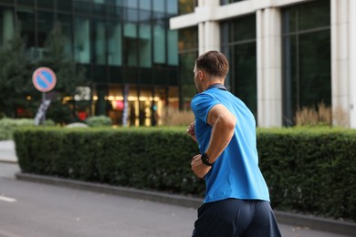 Photo of Man in sportswear running outdoors, back view