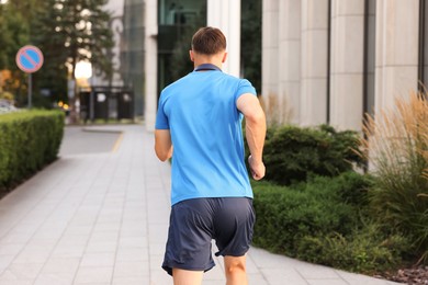 Photo of Man in sportswear running outdoors, back view