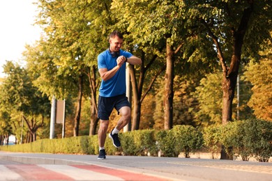Photo of Man checking fitness tracker while running outdoors