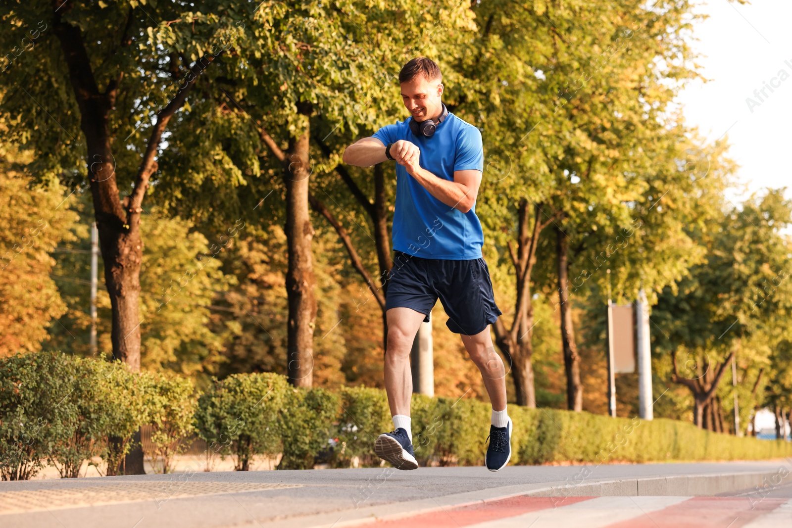Man checking fitness tracker while running outdoors Photo of Man checking fitness tracker while running outdoors