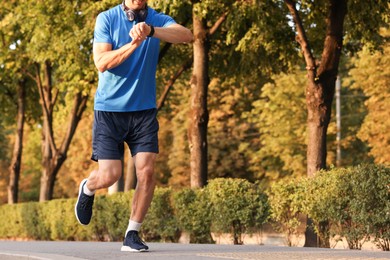Photo of Man checking fitness tracker while running outdoors, closeup. Space for text