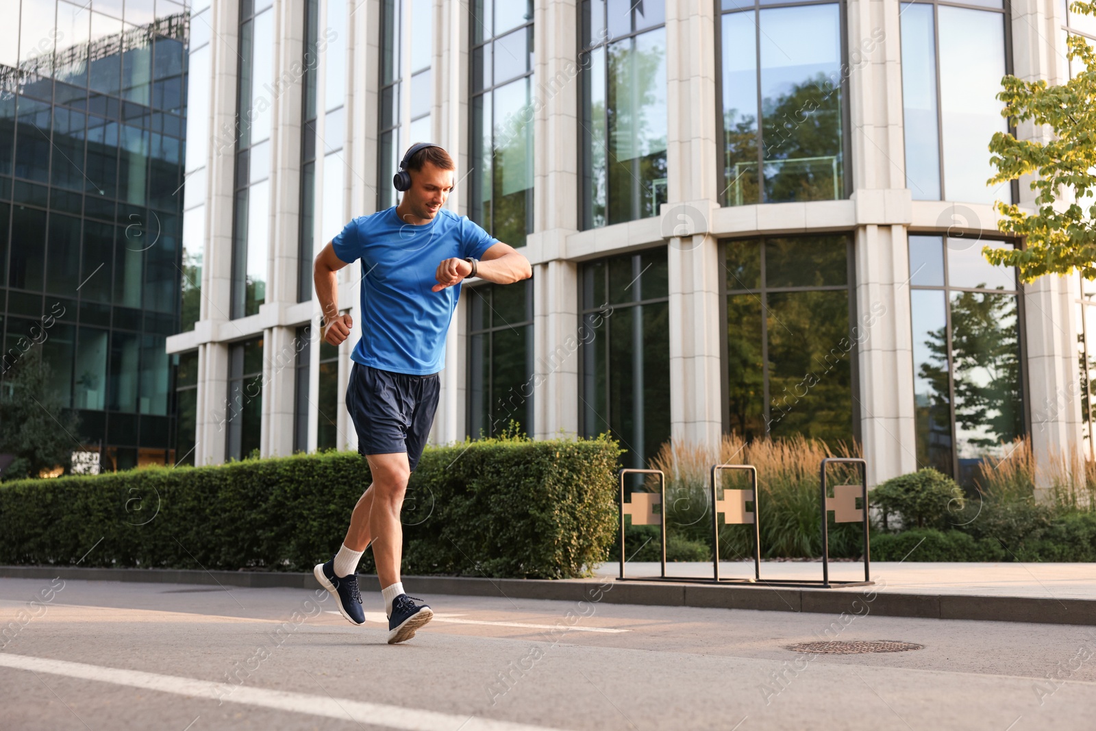 Photo of Man checking fitness tracker while running outdoors, space for text