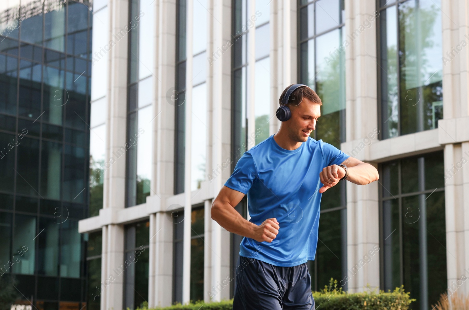 Photo of Man checking fitness tracker while running outdoors, space for text