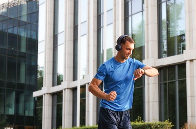 Photo of Man checking fitness tracker while running outdoors, space for text