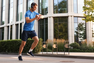 Photo of Man checking fitness tracker while running outdoors, space for text