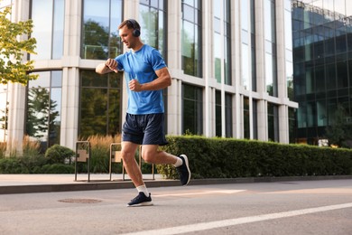 Photo of Man checking fitness tracker while running outdoors, space for text