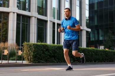 Photo of Man in sportswear running on city street, space for text