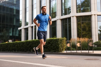 Photo of Man in sportswear running on city street, space for text