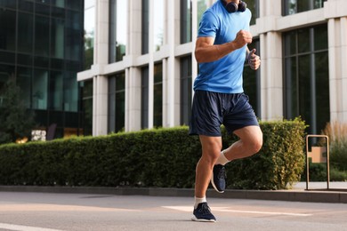 Photo of Man in sportswear running on city street, closeup. Space for text